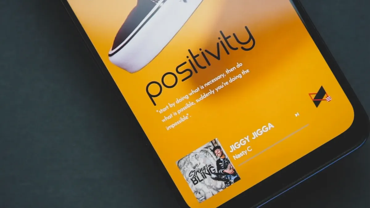 Vibrant mobile screen displaying a positivity message and music by Jiggy Jigga.