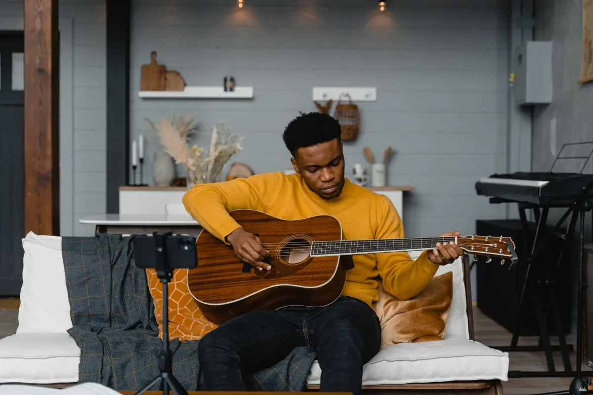 A young man playing acoustic guitar in a cozy home studio setting, perfect for music lovers.